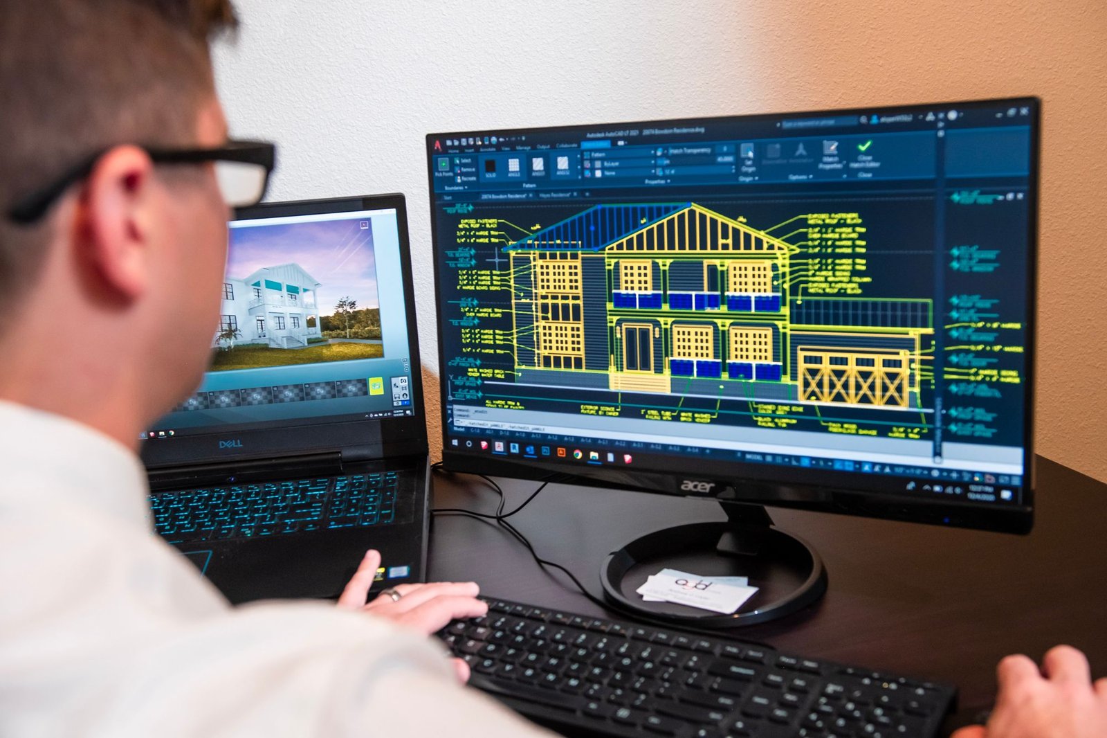 Architect at a dual-monitor workstation reviewing a CAD elevation drawing — the working scenario CFAeX is written to test